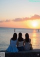 Three women sitting on a wall looking at the sunset.